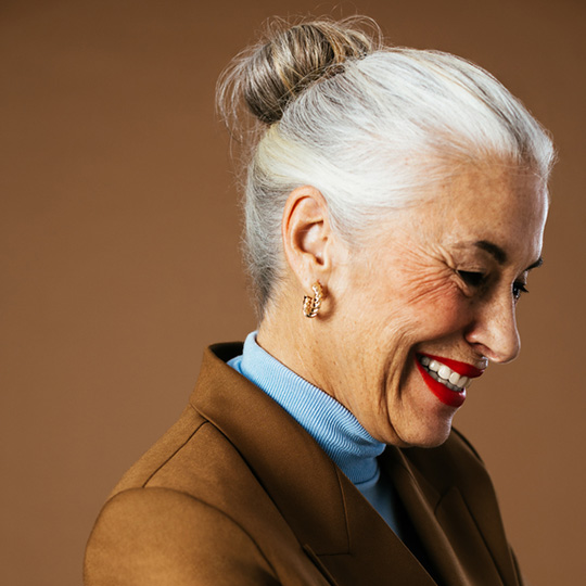 Smartly dressed woman with grey bun smiling and looking to side
